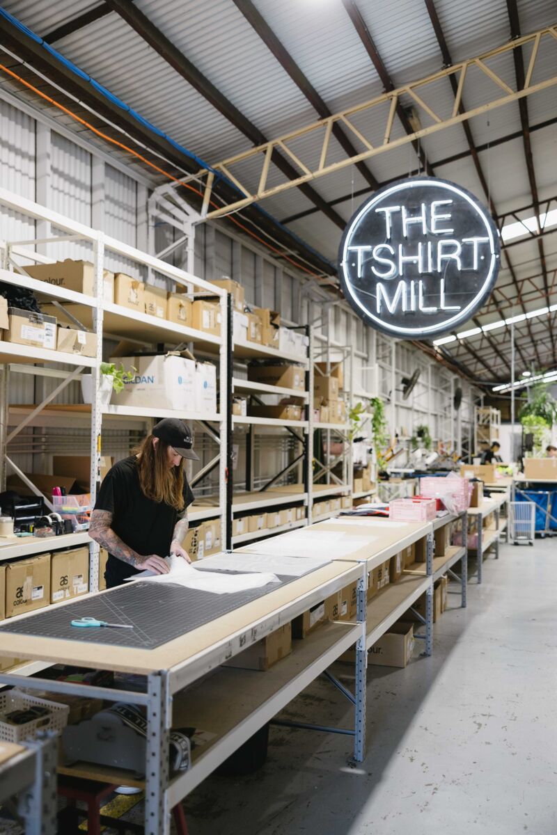 The Tshirt Mill workshop in Newstead, staff working under the neon sign